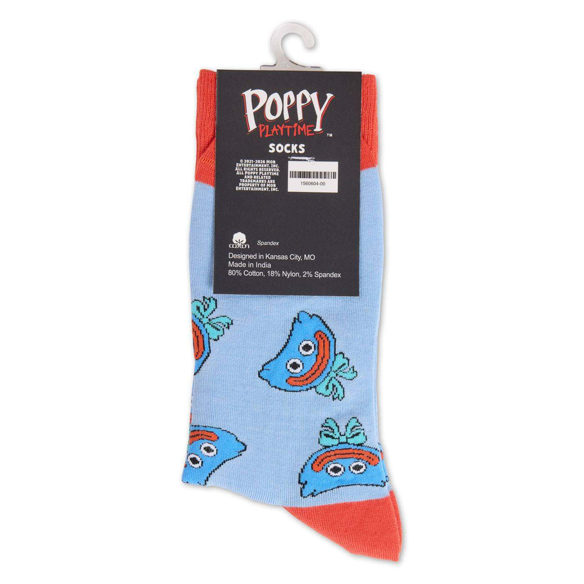 A pair of light blue novelty socks with a repeating smiling huggy wuggy face pattern and coral-red toes and heels, hanging from a white plastic hanger with a black Poppy Playtime brand label.